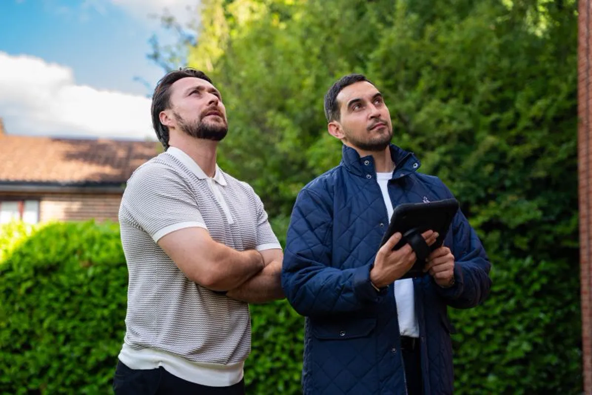 Two Novello surveyors standing outside a house, looking up at the roofline together, one holding a tablet