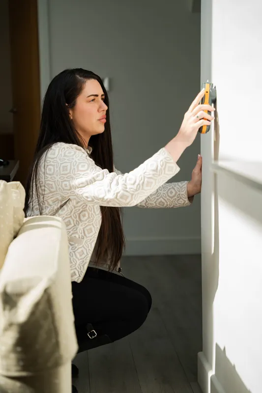 A Novello surveyor taking a damp reading from a wall with a moisture meter